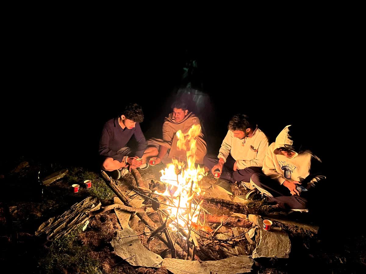 Guests warming up around the campfire at Thatharana Trek after dark