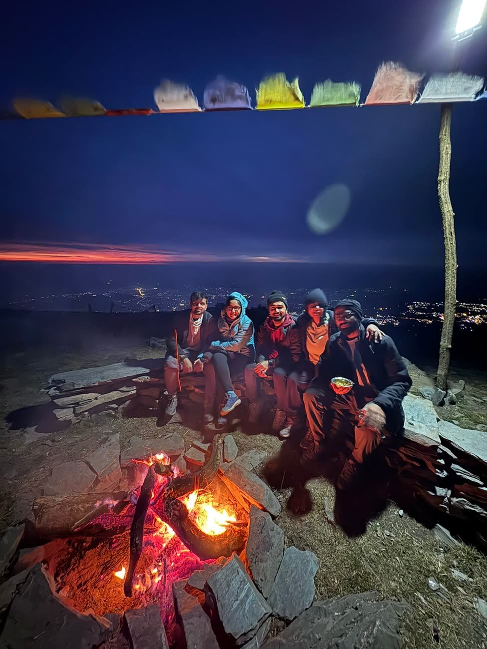 Guests gathered around the evening bonfire with the valley lights below