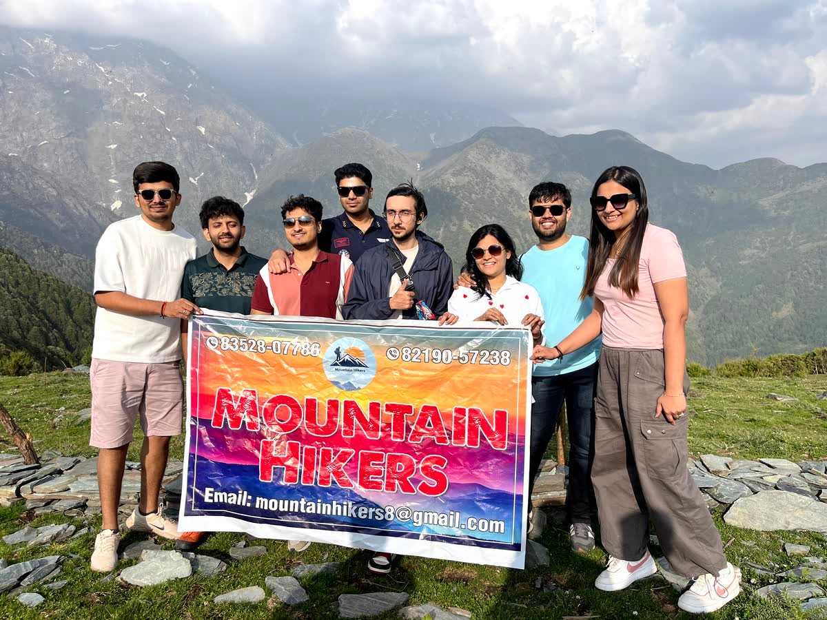 A group of trekkers holding the Mountain Hikers banner at the campsite