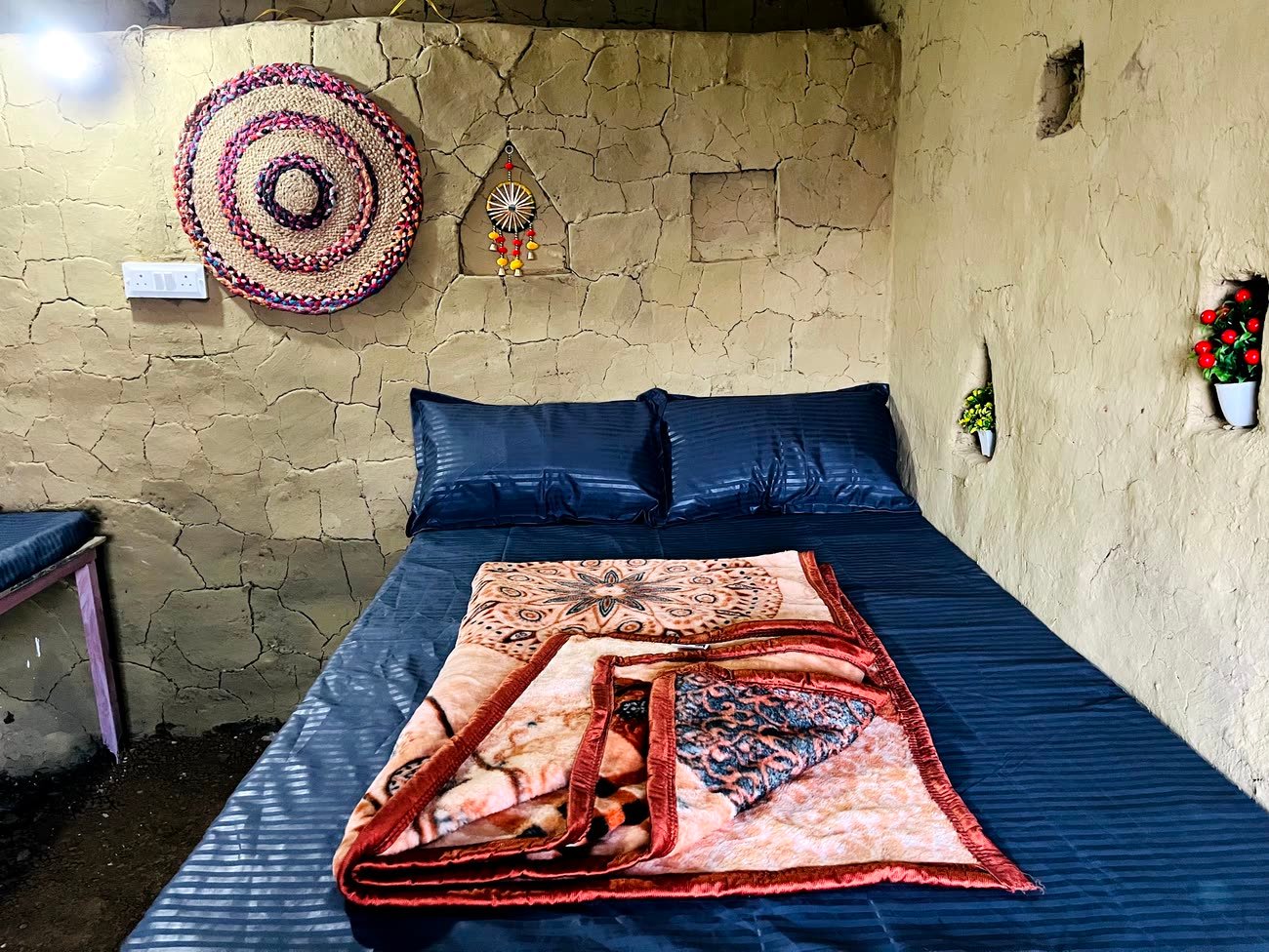 Inside a traditional Himachali mudhouse room with a made-up double bed