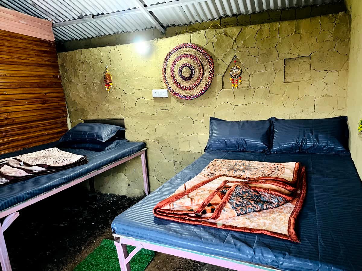 Mudhouse room at Thatharana Trek set up with two beds under a mud-plastered wall