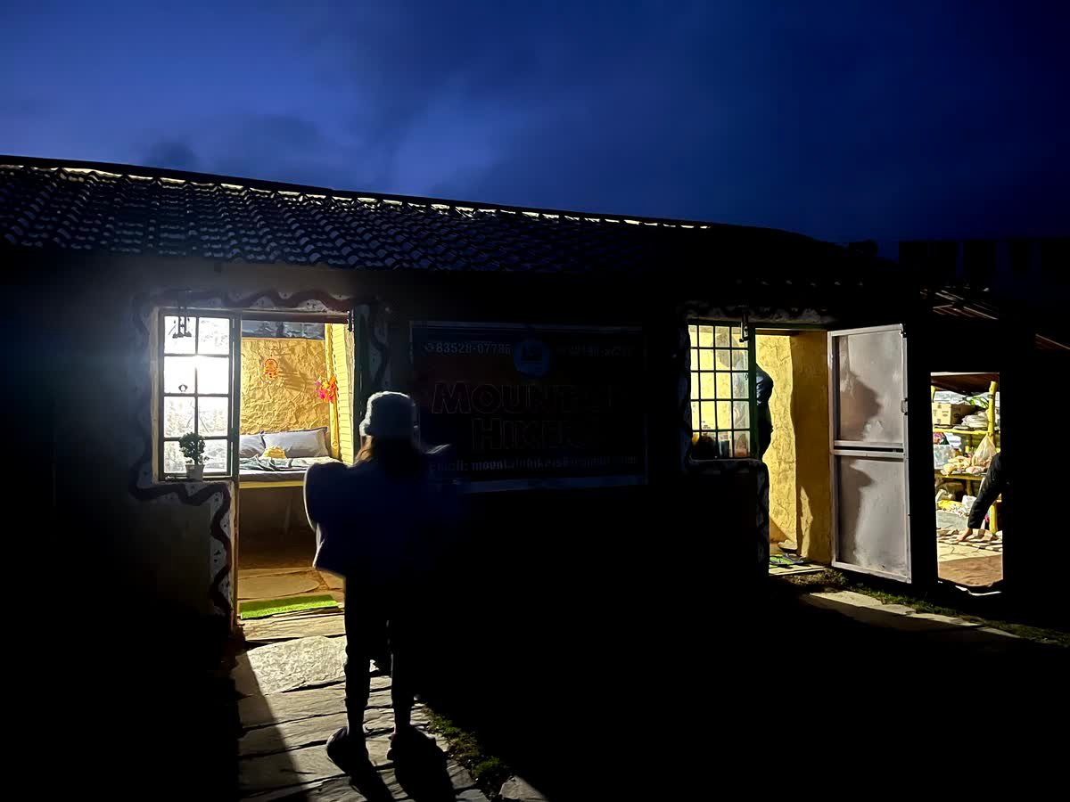 Mudhouse rooms lit up after dark at the Thatharana Trek campsite