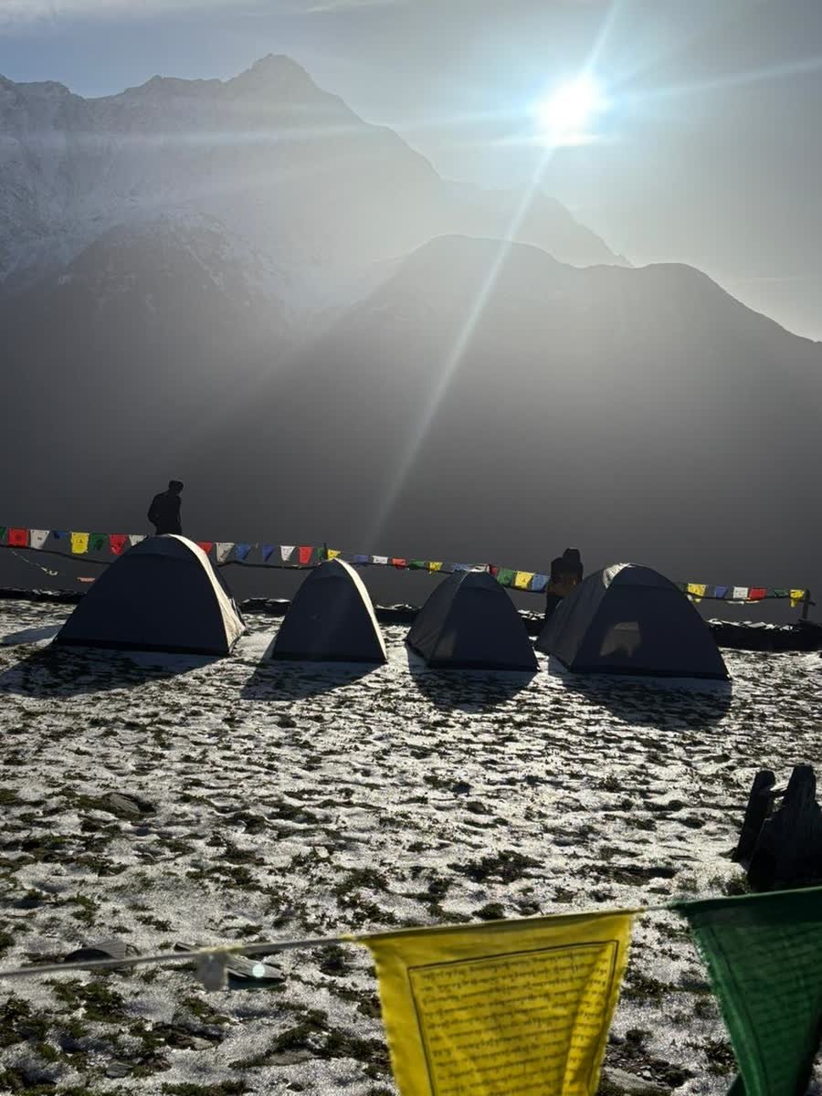 Sunrise over the tents at Thatharana Trek with prayer flags strung across the campsite