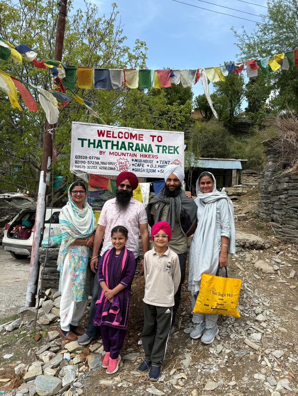 A family at the Thatharana Trek by Mountain Hikers welcome signboard